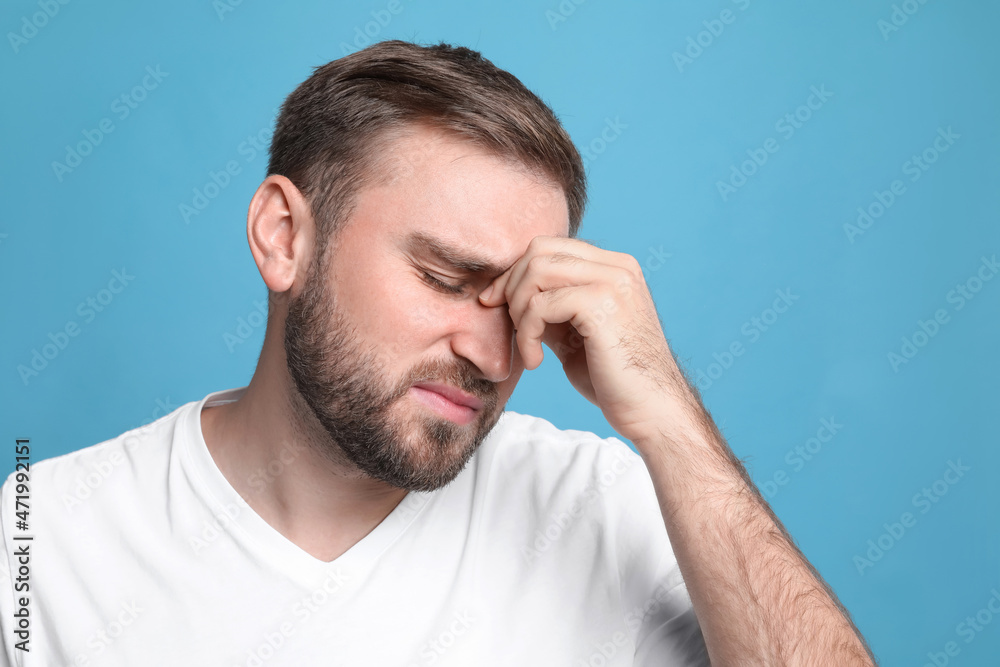 Young man suffering from headache on light blue background Young man suffering from headache on light blue background