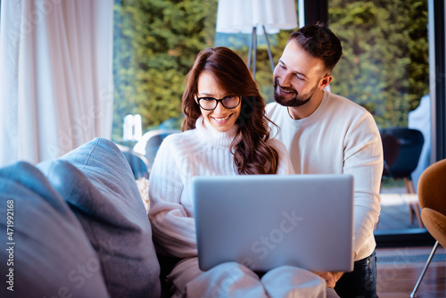 Happy couple using laptop while relaxing on the sofa at home