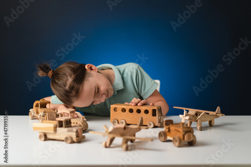 School boy playing, hands holding with wooden toys on white table, while staying at home on blue enlighted background photo