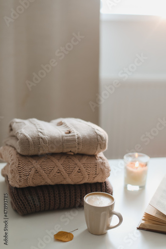 cozy home atmosphere and still life with coffee, candle and sweaters