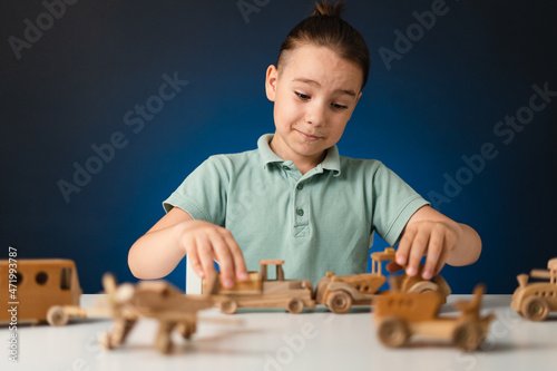 School boy playing, hands holding with wooden toys on white table, while staying at home on blue enlighted background photo