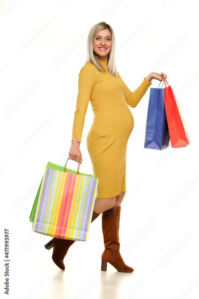 Young happy pregnant woman in long yellow dress posing with a shopping bags Young happy pregnant woman in long yellow dress posing with a shopping bags