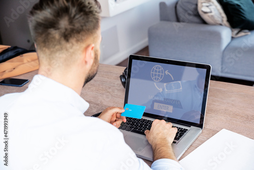 Man sitting on the couch at home and banking online