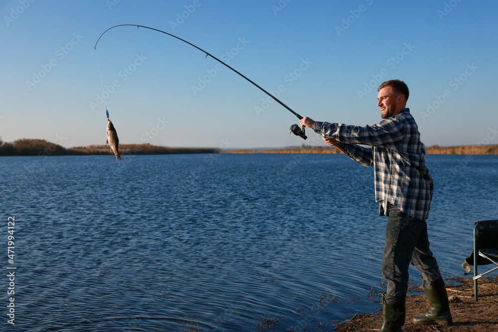 Fisherman catching fish with rod at riverside Fisherman catching fish with rod at riverside