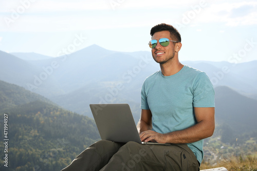 Man working with laptop in mountains on sunny day © New Africa