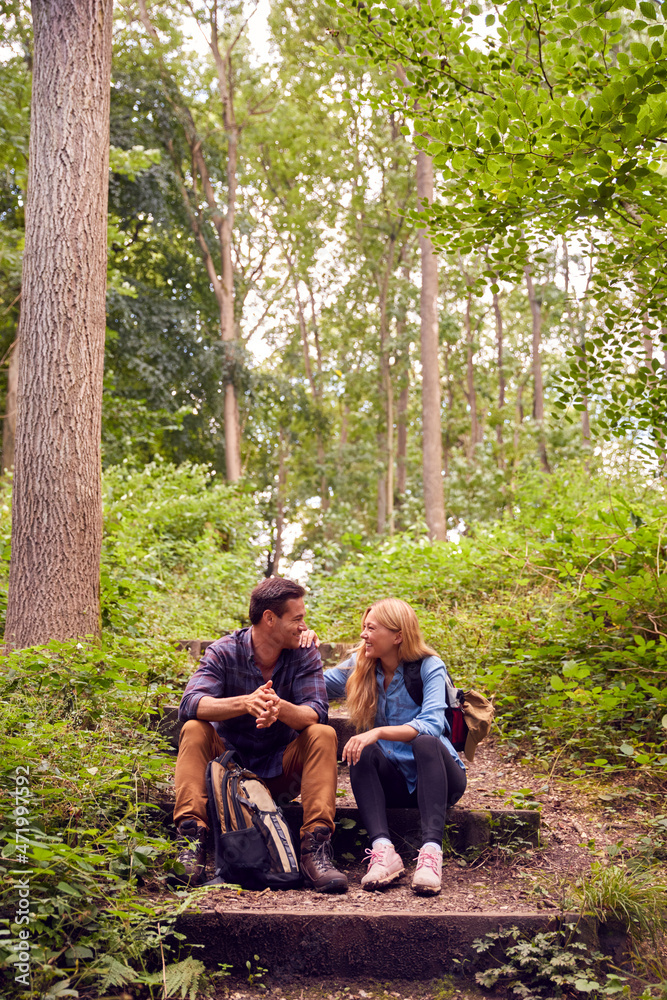 Couple In Countryside Hiking Along Path Through Forest Together Taking a Break Sitting Down Couple In Countryside Hiking Along Path Through Forest Together Taking a Break Sitting Down