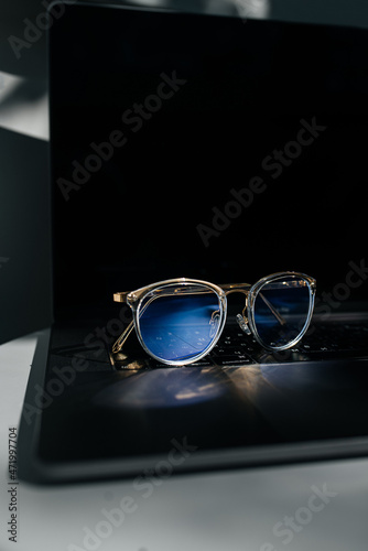 Computer glasses on laptop keyboard, close up. Blue light blockers, eye fatigue problem concept