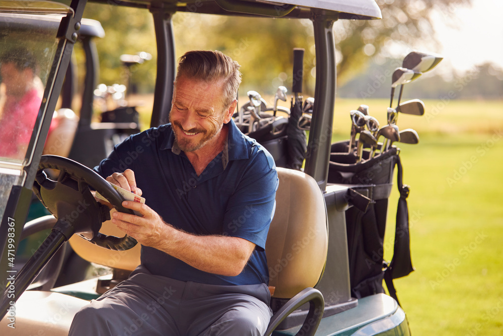 Mature Man Sitting In Buggy Playing Round On Golf And Checking Score Card Mature Man Sitting In Buggy Playing Round On Golf And Checking Score Card