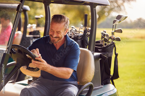 Mature Man Sitting In Buggy Playing Round On Golf And Checking Score Card