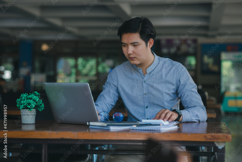 Professional young Asian businessman using computer laptop and Talking On Phone Working On Laptop.	