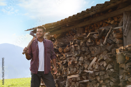Happy man with ax near wood pile outdoors photo