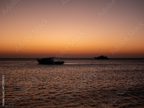 Beautiful sunrise on the Red Sea in Egypt. Dark silhouettes of yachts on the horizon.