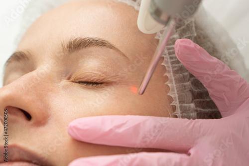 Obraz na plátně close-up Doctor cosmetologist makes the procedure of laser dermal rejuvenation of the eyelids of the skin around the eyes to the patient