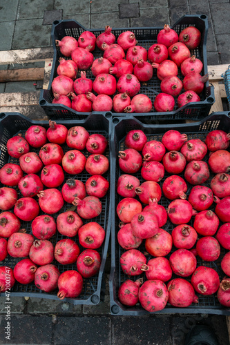Ripe pomegranate fruits in open plastic boxes. Selling fruit in the market. Healthy eating. Pomegranate fruits are eaten raw, in cooked dishes, in drinks to make pomegranate juice.