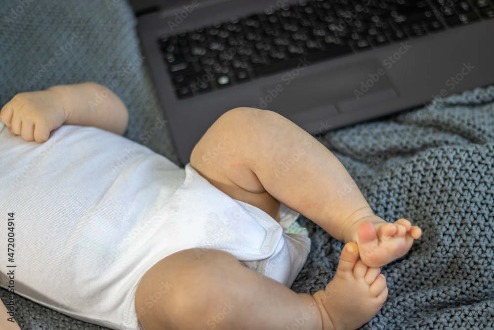 Fototapeta premium baby little boy toddler infant newborn in woman arms.female hands on black keyboard on a laptop.working in maternity leave. different finance sources.money, work from home.baby head on mom's shoulder
