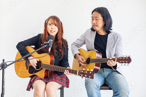 Asian family duo band with two guitarist of father and daughter on white background while playing live acoustic concert for music, artist, musician concept photo