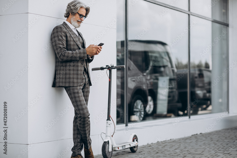 Middle aged business man riding scooter in a classy suit