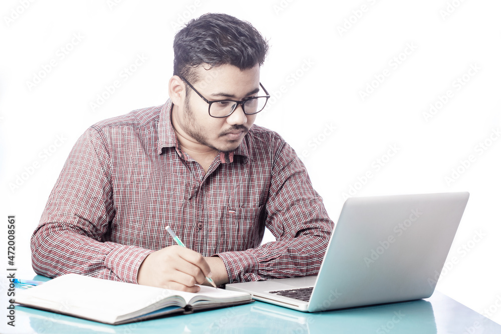 business man writing on diary notepad with pencil looking at laptop screen business man writing on diary notepad with pencil looking at laptop screen