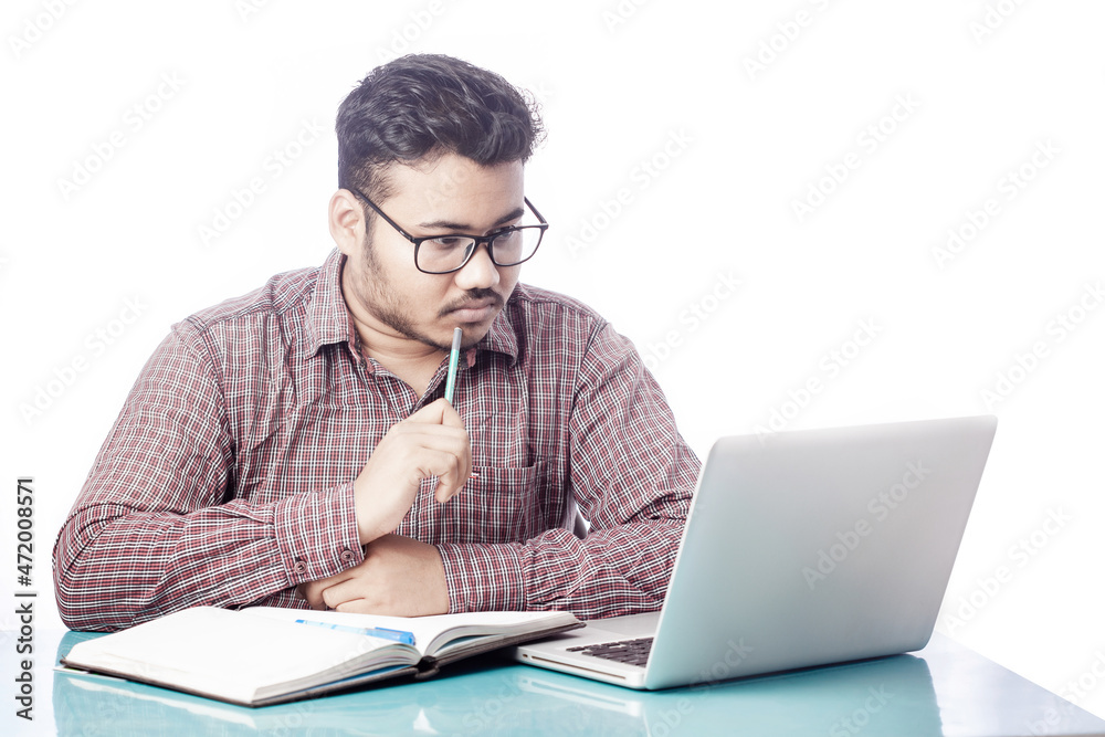 student thinking with pencil on mouth looking at computer screen on a desk student thinking with pencil on mouth looking at computer screen on a desk