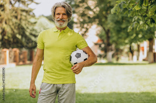 Middle aged football player with football ball