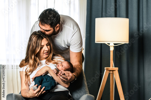 Woman and man holding a newborn. Mom, dad and baby. Portrait of smiling family with newborn on the hands. Happy family concept. Copy space
 photo