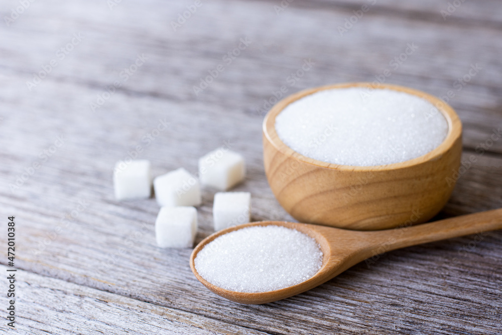 White sand sugar in wooden bowl and wooden spoon and cube sugar on wood table background. White sand sugar in wooden bowl and wooden spoon and cube sugar on wood table background.