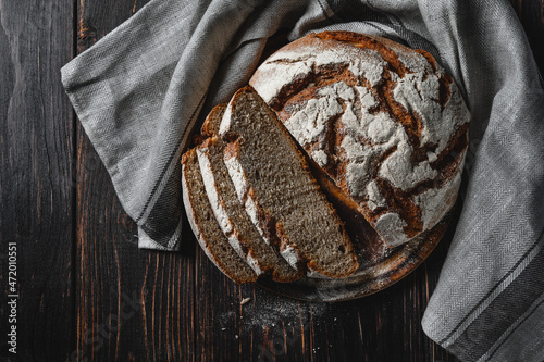 Homemade rye bread. Sliced rye bread in a round shape on a wooden background in a rustic style with towel. Top view. photo