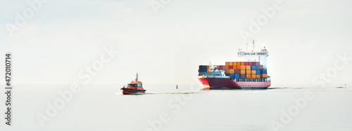 Fotografiet Large cargo container ship being led by the pilot boat