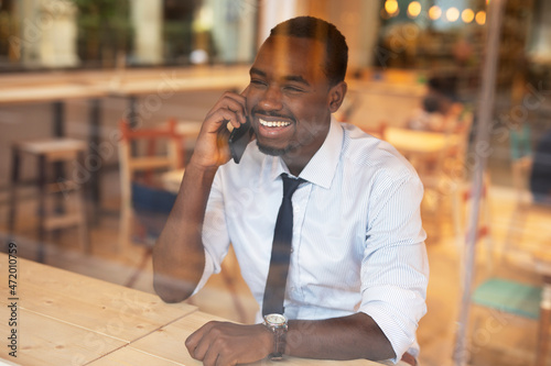 Businessman drinking coffee in cafe. Handsome African man talking to the phone while enjoying in fresh coffee.
