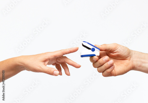 Woman using fingertip pulse oximeter on white background, close up