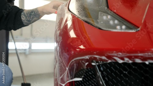 Close up to PPF installation process on a front headlight and hood. PPF is a Paint Protection Film which protect paint from scratches and stone chips. Concept of: Guard, Protect, Car, New, Work.	
