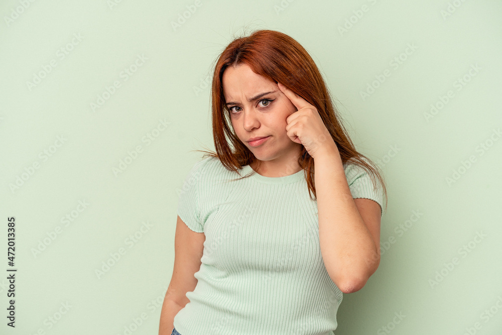 Young caucasian woman isolated on green background pointing temple with finger, thinking, focused on a task. Young caucasian woman isolated on green background pointing temple with finger, thinking, focused on a task.