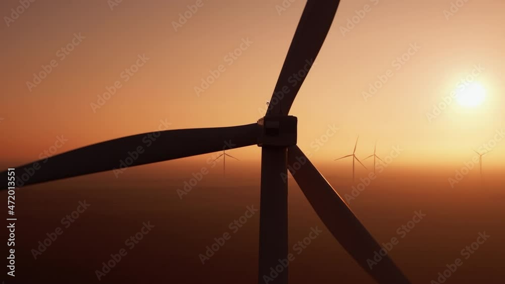 Modern wind turbine with powerful propeller rotates at offshore station producing alternative energy against sunset close aerial view