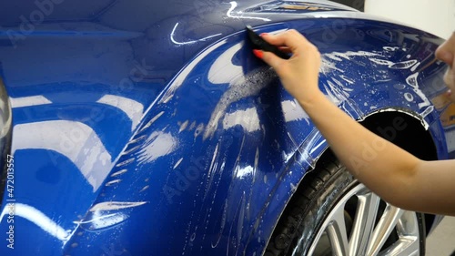 Close up to PPF installation process on a front headlight and hood. PPF is a Paint Protection Film which protect paint from scratches and stone chips. Concept of: Guard, Protect, Car, New, Work.	
