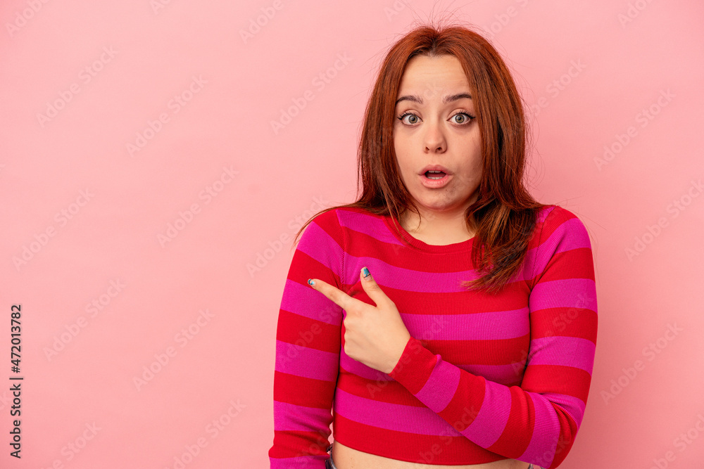 Obraz premium Young caucasian woman isolated on pink background pointing to the side
