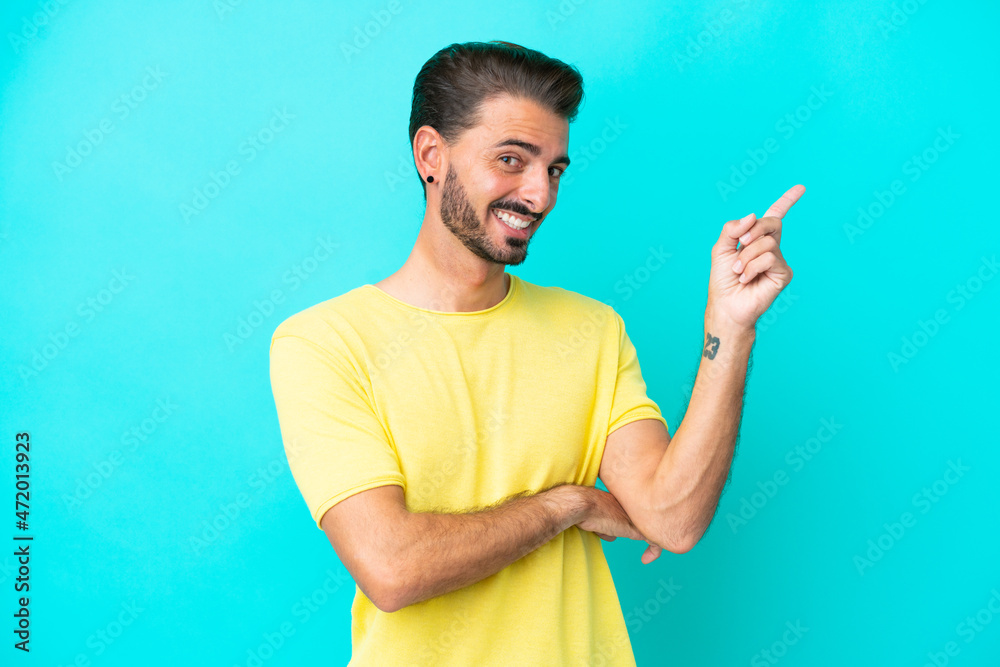 Young caucasian man isolated on blue background happy and pointing up Young caucasian man isolated on blue background happy and pointing up