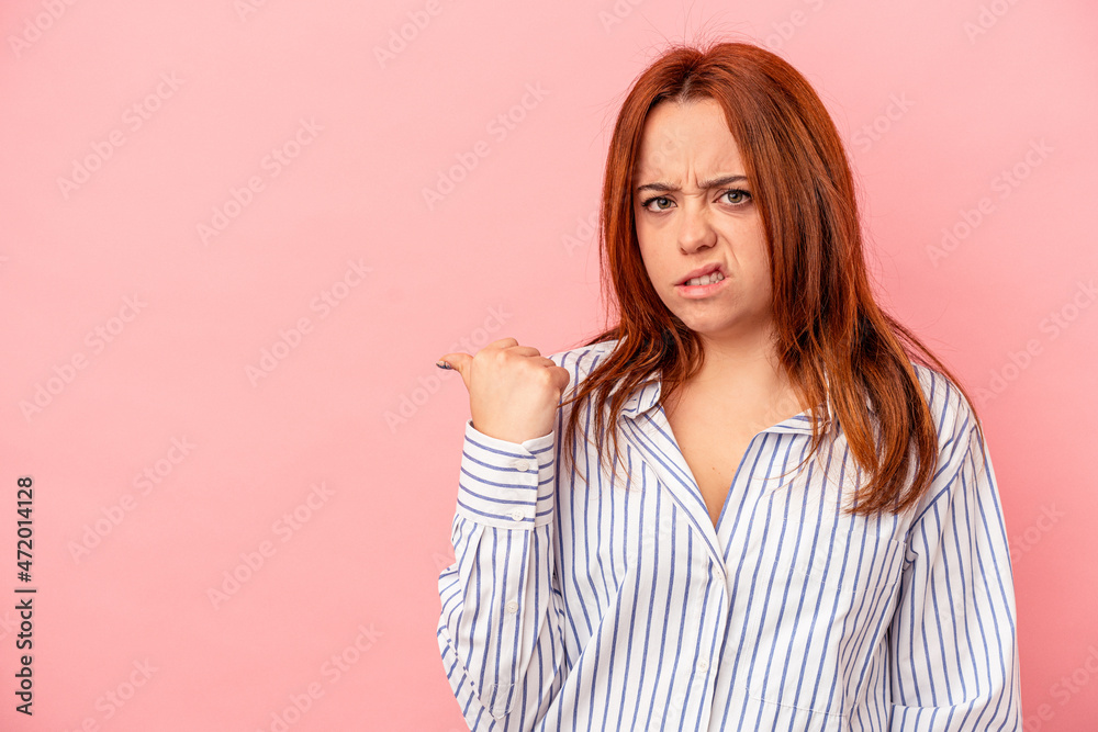 Young caucasian woman isolated on pink background shocked pointing with index fingers to a copy space. Young caucasian woman isolated on pink background shocked pointing with index fingers to a copy space.