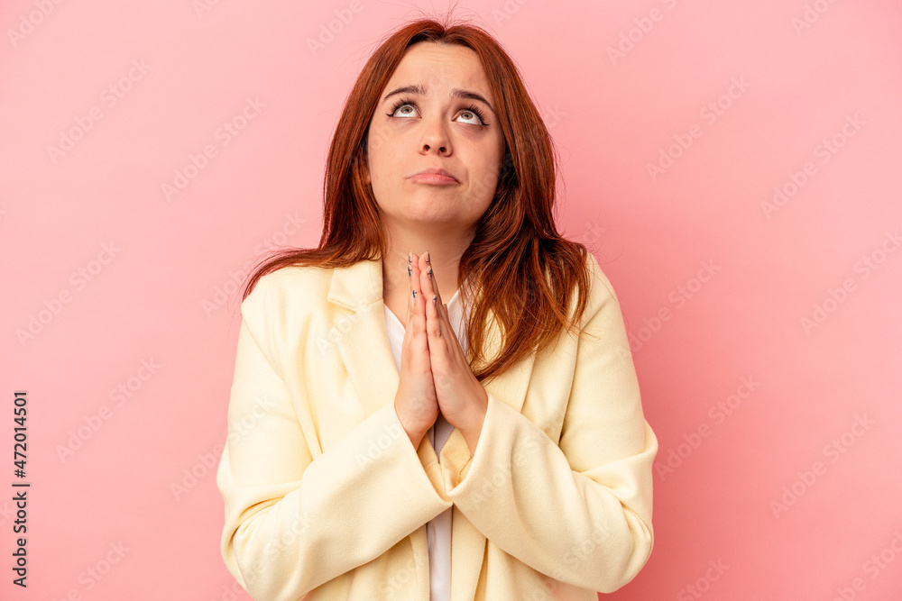 Young caucasian woman isolated on pink background holding hands in pray near mouth, feels confident. Young caucasian woman isolated on pink background holding hands in pray near mouth, feels confident.