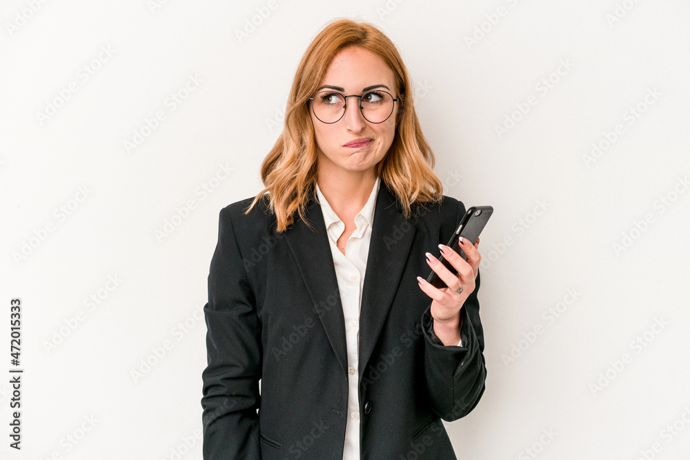 Young business caucasian woman holding mobile phone isolated on white background confused, feels doubtful and unsure.