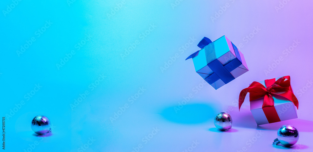 Neon Christmas winter background. Xmas gift box with shine lights. Holiday gifts, decoration bauble ball on neon abstract gradient backdrop. Happy new year copy space. Neon Christmas winter background. Xmas gift box with shine lights. Holiday gifts, decoration bauble ball on neon abstract gradient backdrop. Happy new year copy space.