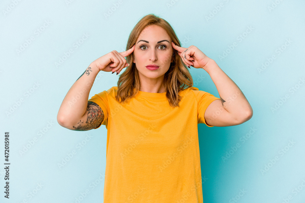 Young caucasian woman isolated on blue background focused on a task, keeping forefingers pointing head. Young caucasian woman isolated on blue background focused on a task, keeping forefingers pointing head.