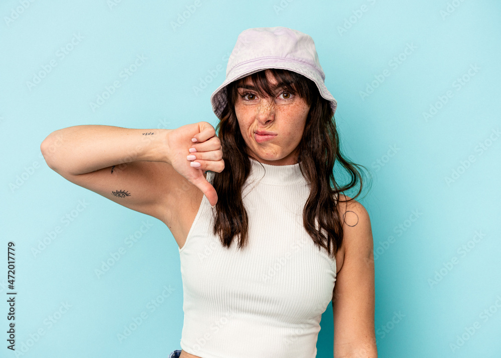 Young Argentinian woman isolated on blue background showing thumb down, disappointment concept. Young Argentinian woman isolated on blue background showing thumb down, disappointment concept.