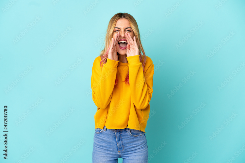 Young woman over isolated blue background shouting and announcing something Young woman over isolated blue background shouting and announcing something