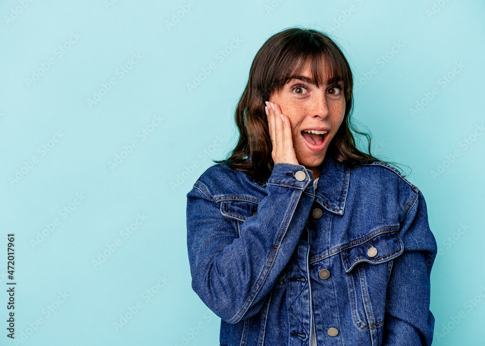 Young Argentinian woman isolated on blue background shouts loud, keeps eyes opened and hands tense. Young Argentinian woman isolated on blue background shouts loud, keeps eyes opened and hands tense.