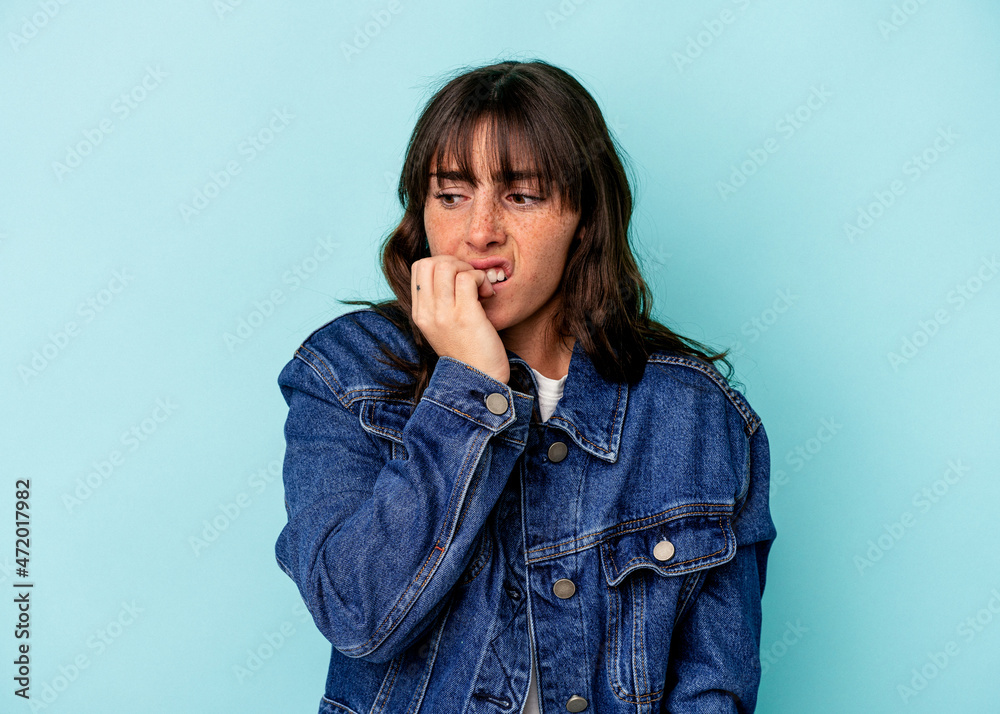 Young Argentinian woman isolated on blue background biting fingernails, nervous and very anxious. Young Argentinian woman isolated on blue background biting fingernails, nervous and very anxious.