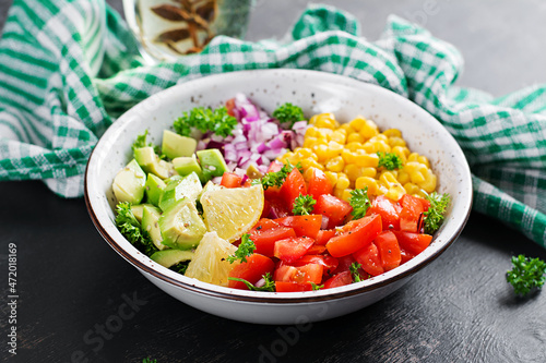 Salad with avocado, tomatoes, red onions and sweet corn in bowl. Vegetarian buddha bowl. Vegan food.