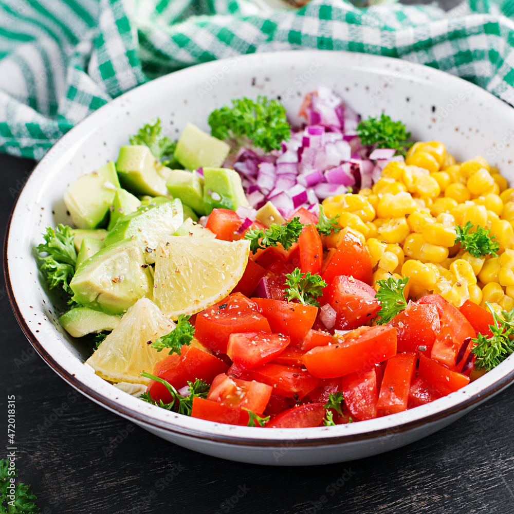 Salad with avocado, tomatoes, red onions and sweet corn in bowl. Vegetarian buddha bowl. Vegan food.