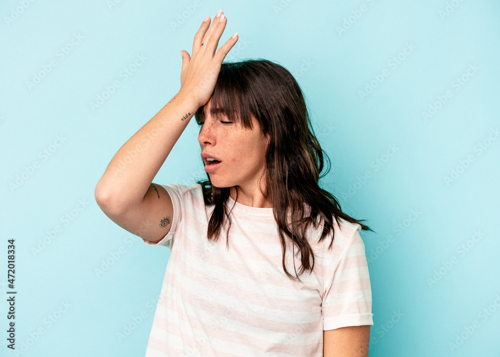 Young Argentinian woman isolated on blue background forgetting something, slapping forehead with palm and closing eyes.