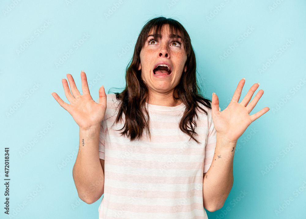 Young Argentinian woman isolated on blue background screaming to the sky, looking up, frustrated. Young Argentinian woman isolated on blue background screaming to the sky, looking up, frustrated.