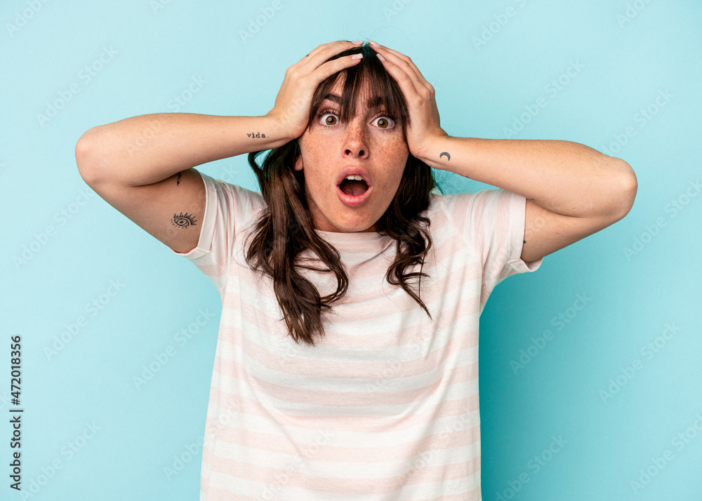 Young Argentinian woman isolated on blue background surprised and shocked. Young Argentinian woman isolated on blue background surprised and shocked.